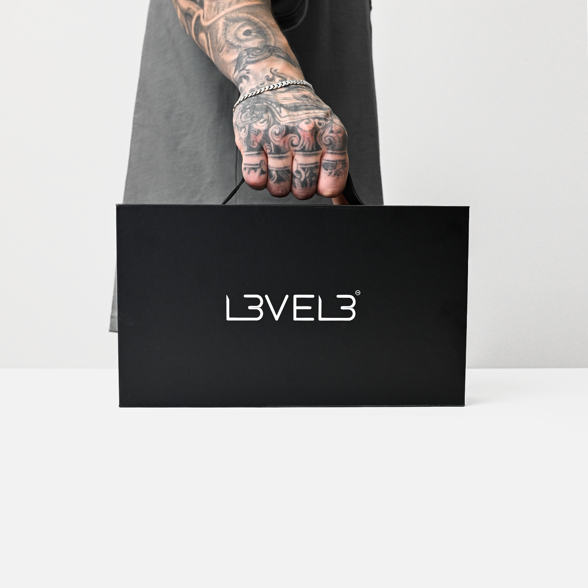 Person holding a black box with 'L3VEL3' logo on a white background