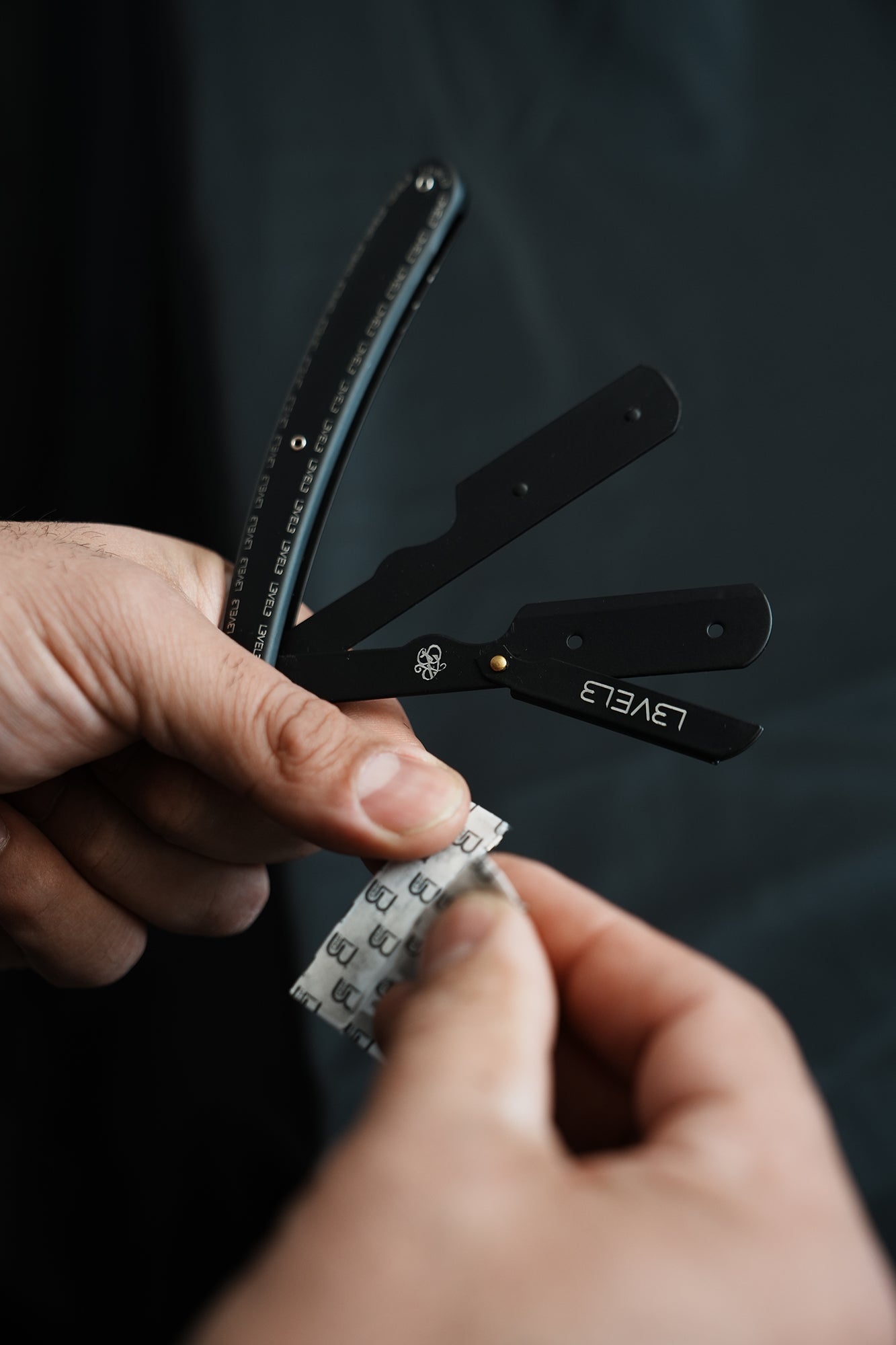 Person holding a L3VEL3 butterfly with multiple blades against a dark background